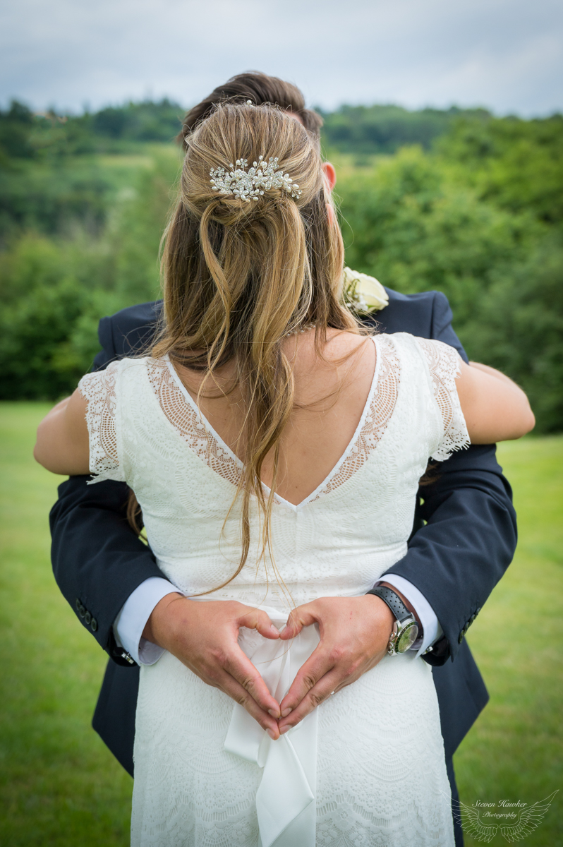 Groom makes heart shape at Brides back