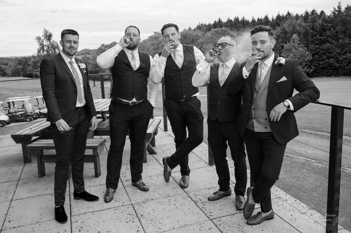 Groom and friends smoking cigars at wedding